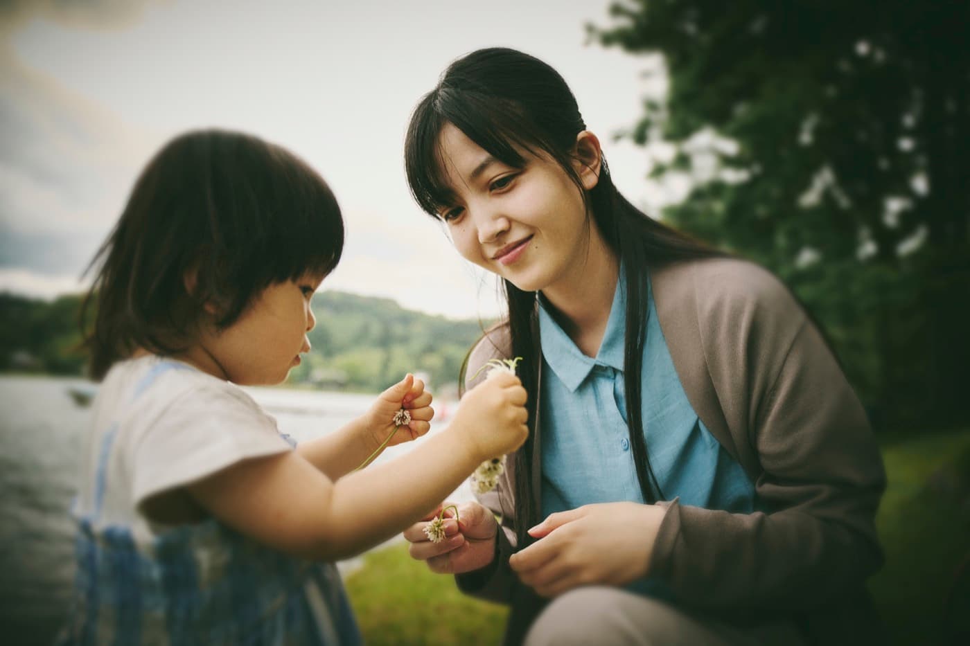 湖畔で律ちゃんと花を交わす久保史緒里さん